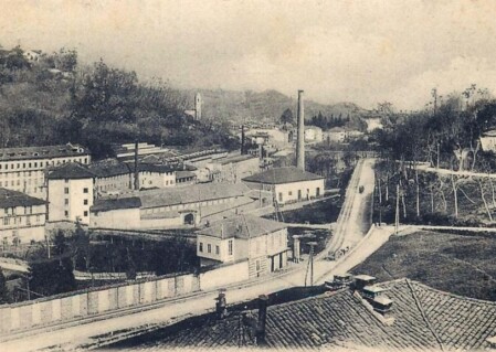 Panoramica storica di un insediamento industriale tessile a Biella con ciminiere e fabbricati, anni 1920